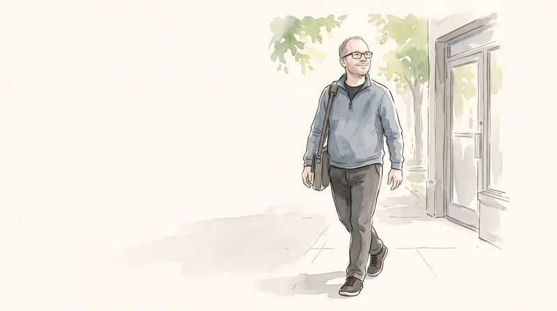 Man walking out onto a sunny sidewalk, standing tall and smiling